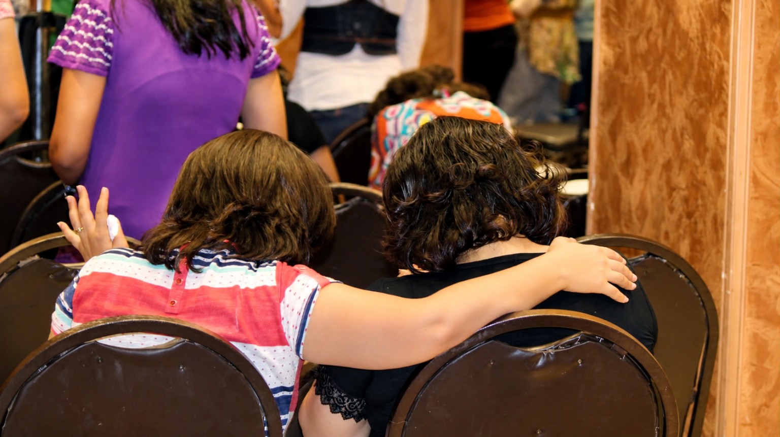 A young person offering encouragement with an arm around another person